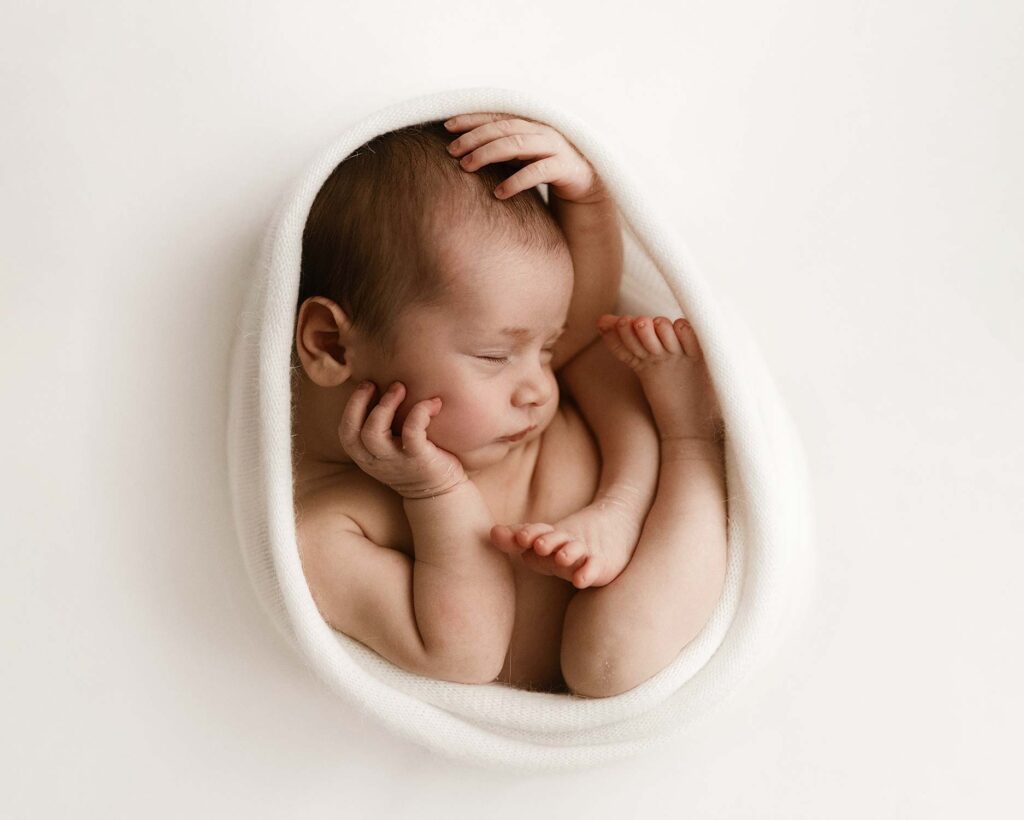 Vauva- ja newborn-kuvaus Helsinki - vastasyntynyt vauva nukkuu sykerössä mustavalkokuvassa