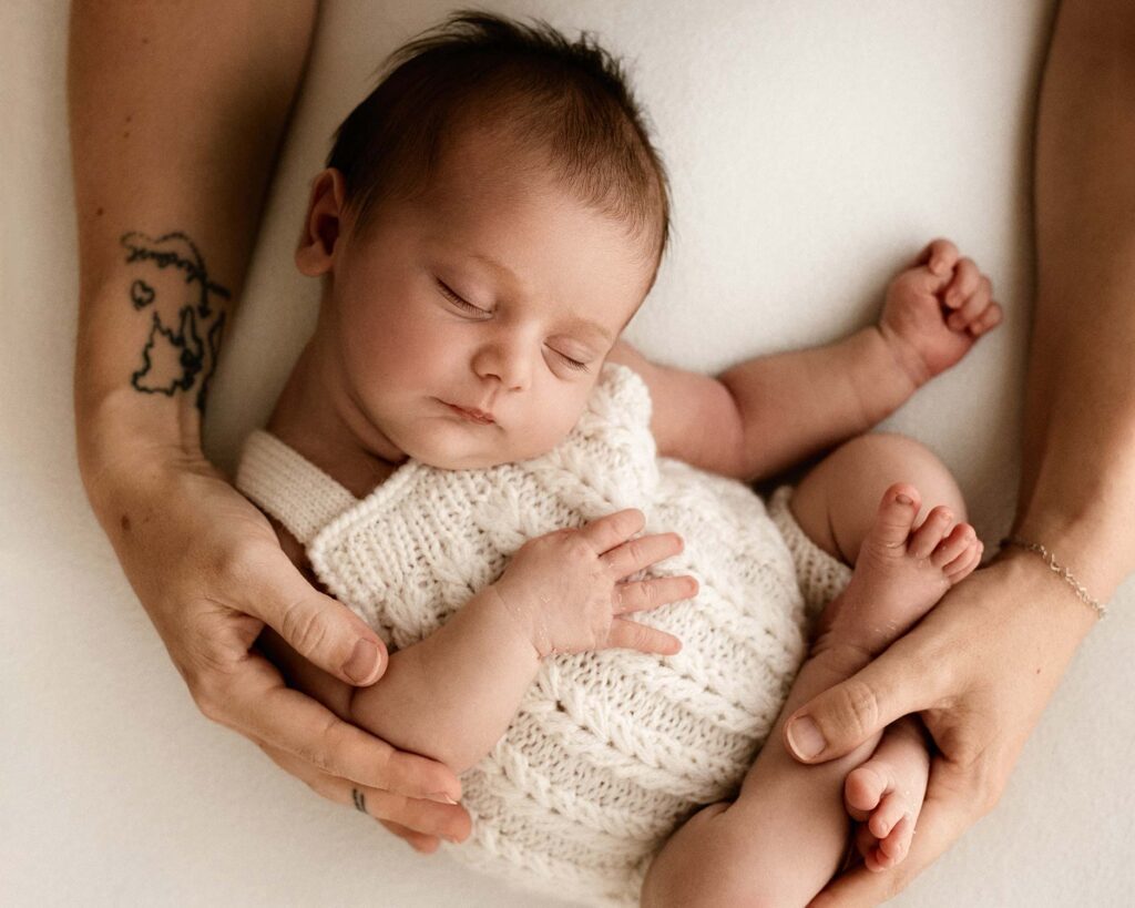Newborn kuvaus Vantaa - vastasyntynyt vauva nukkuu äidin käsien ympäröimänä